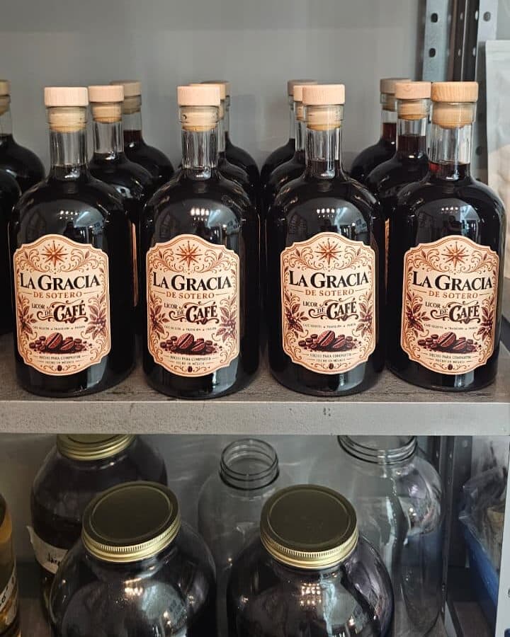 Un lote de botellas de Licor de Café en una estantería; debajo, frascos de vidrio.